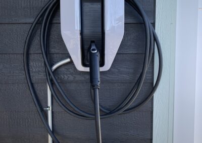 Ford electric vehicle charging station mounted on a wall with coiled charging cable.